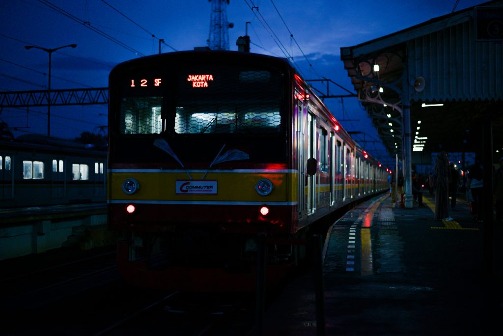 A commuter train at Jakarta Kota Station illuminated at night, highlighting urban travel.